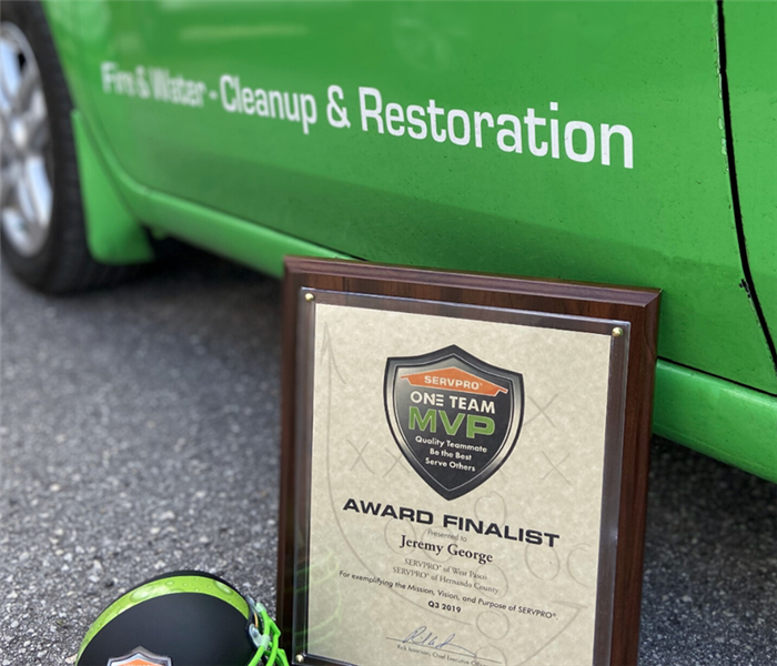 picture of a framed award on the road in front of a green car